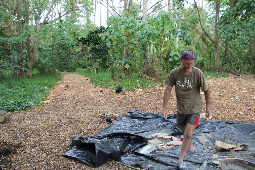 The race to beat the rain is on as Wayne prepares the Polythene to mix concrete.